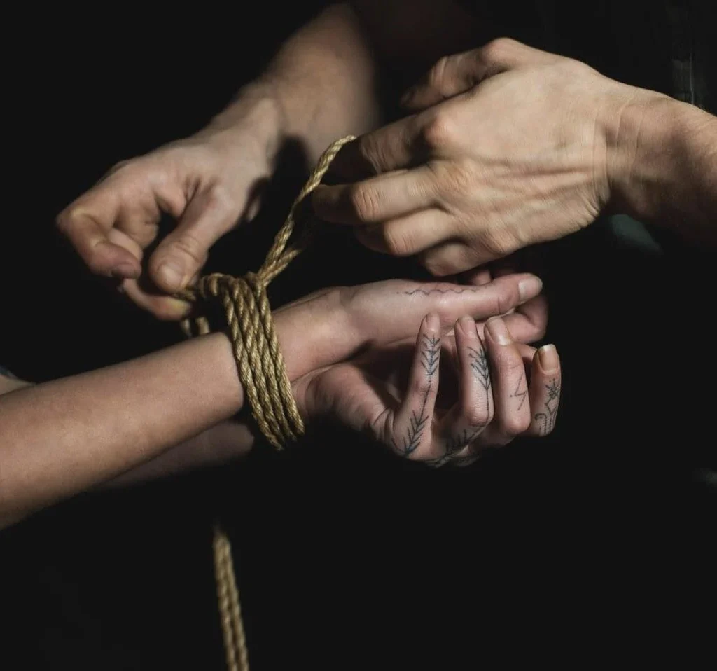 Nahaufnahme einer Handgelenksfesselung mit goldenem Seil – Technik und Form beim Shibari