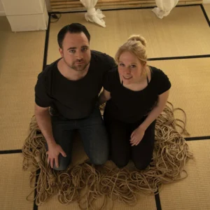 Shibari Kurs für Paare: Paar kniet lächelnd auf Tatami zwischen Seilen – Kursraum von Shibari Münster in Greven