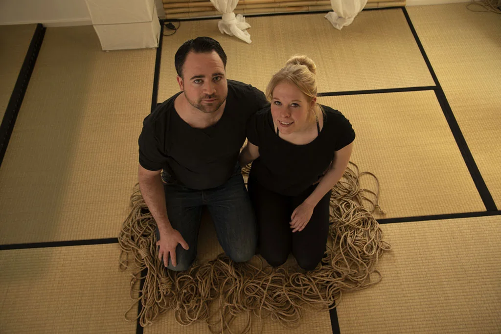 Paar kniet lächelnd auf Tatami zwischen Seilen – Kursraum von Shibari Münster in Greven
